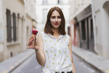 Young woman with ice cream standing on street - AFVF09071