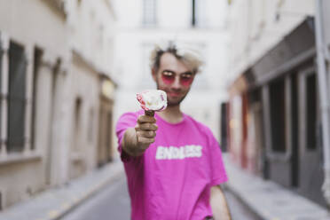 Young gay man wearing pink T-shirt offering ice cream stock photo