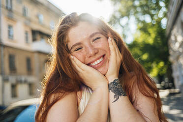 Happy redhead woman with hands on chin - OYF00468