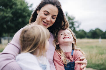 Smiling woman talking with girls at park - ASGF01287