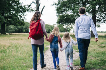 Familie hält sich beim gemeinsamen Spaziergang im Park an den Händen - ASGF01317