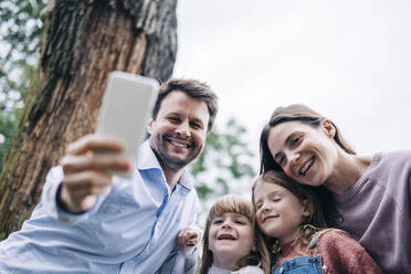 Lächelnder Vater nimmt Selfie mit Familie durch Handy - ASGF01319