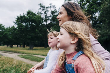 Smiling daughters with mother at park - ASGF01325