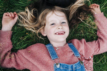 Smiling girl resting while lying on grass - ASGF01342