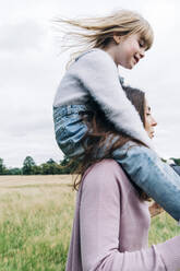 Mother carrying smiling daughter while playing on meadow - ASGF01348