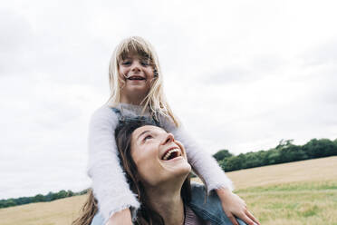 Playful woman carrying girl while playing - ASGF01351