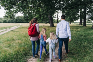 Töchter halten die Hände der Eltern beim Spaziergang im Park - ASGF01366