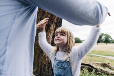 Smiling daughter playing with father at park during vacation - ASGF01372