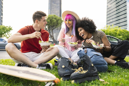 Fröhliche junge multiethnische Freunde essen Salat im Park - JCCMF03686