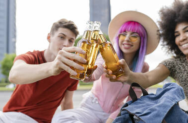 Multi-ethnic male and female friends toasting drinks at park - JCCMF03689