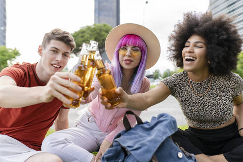 Multiethnische männliche und weibliche Freunde, die im Park sitzen und feiern - JCCMF03690