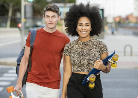 Junges Paar geht mit Skateboards in der Hand spazieren - JCCMF03698