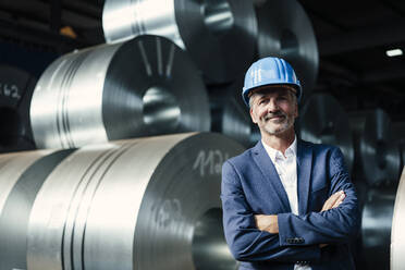 Confident businessman with arms crossed standing at steel mill - GUSF06214