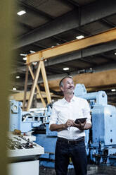 Male professional with digital tablet standing at steel mill - GUSF06233