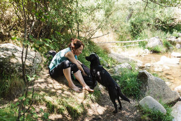 Mittlere erwachsene Frau und Hund schauen sich im Wald an - MRRF01405