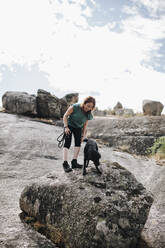 Smiling woman and dog standing on rock - MRRF01408