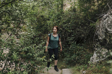 Mid adult woman walking in forest during weekend - MRRF01421