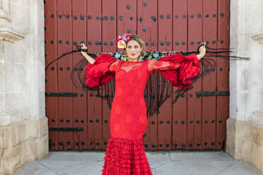 Weibliche Flamenco-Tänzerin hält Schal, während sie sich vor einer Tür dreht - JRVF01704