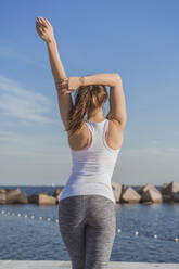 Woman stretching hand while looking at sea - AFVF09109
