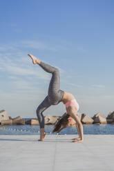 Woman bending backwards while practicing acroyoga on boardwalk - AFVF09111