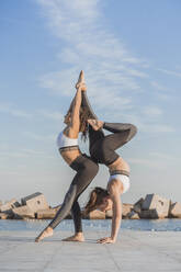 Junge Frauen üben Acroyoga an der Strandpromenade - AFVF09113