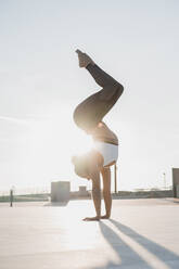 Woman doing handstand during sunny day - AFVF09114