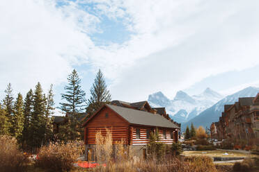 Malerische Herbstlandschaft mit Holzhäusern in der Nähe des Flusses vor verschneiten Bergen in der Stadt Canmore in der Nähe des Banff-Nationalparks in Kanada - ADSF29229