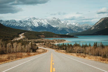 David Thompson Highway going near Abraham Lake and snowy mountains on cloudy day in Banff National Park - ADSF29230