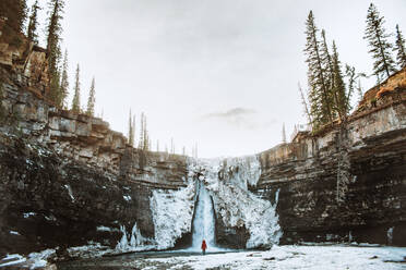 Tourist bewundert den Wasserfall Crescent Falls an einem kalten Wintertag im Banff National Park - ADSF29232
