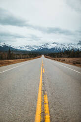 David Thompson Highway vor verschneiten Bergen an einem bewölkten Tag im Banff National Park - ADSF29233