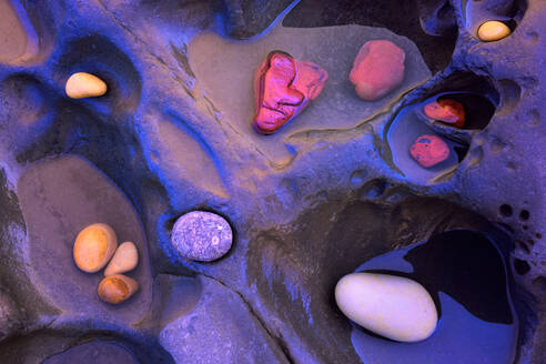 From above of textured background of assorted colorful pebbles placed on rock in water - ADSF29264