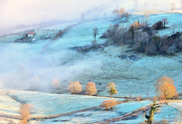 Malerische Infrarotansicht eines Hügels mit Bauernhaus und Bäumen, die mit Rauch bedeckt sind - ADSF29271