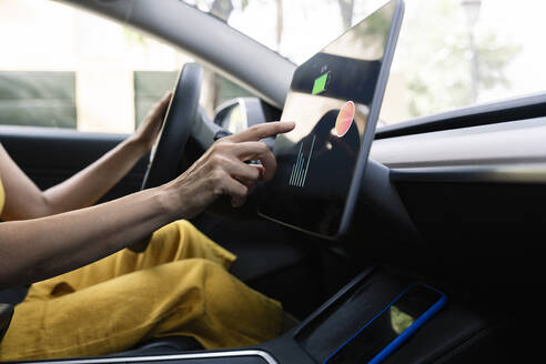 Frau benutzt digitales Tablet beim Fahren eines Elektroautos - JCCMF03711