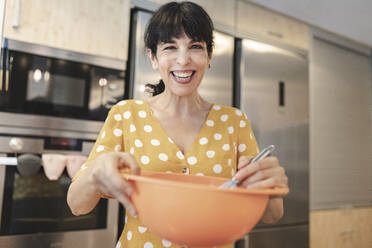 Fröhliche reife Frau bei der Zubereitung von Essen in der Küche zu Hause - JCCMF03755