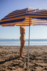 Seitenansicht einer anonymen jungen rothaarigen Frau am Strand an einem sonnigen Tag im Sommer - ADSF29297