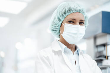 Female pharmacist with surgical cap and protective face mask at pharmacy - JOSEF05389