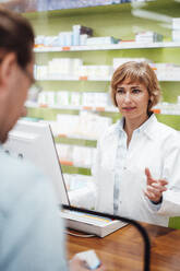 Female pharmacist talking to customer at pharmacy - JOSEF05417