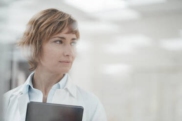 Mature female expertise with digital tablet looking away at pharmacy store - JOSEF05438