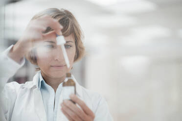 Female pharmacist with pipette examining at laboratory - JOSEF05439