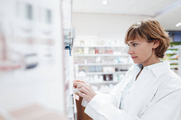 Female pharmacist searching medicine at pharmacy - JOSEF05446