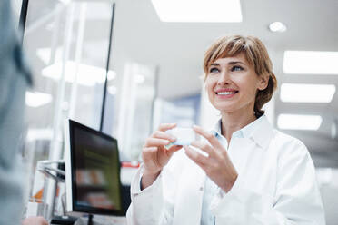 Smiling female pharmacist discussing over medicine with male customer at pharmacy store - JOSEF05458