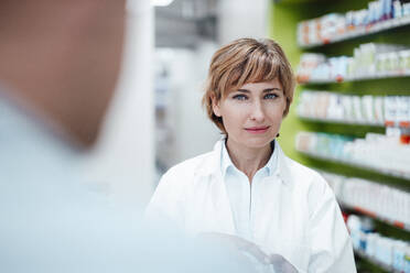 Blond female pharmacist standing at medical store - JOSEF05459