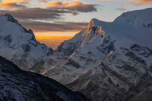Felsige, schneebedeckte Himalaya-Berge mit leuchtend orangefarbenem Sonnenuntergangslicht in Nepal - ADSF29416
