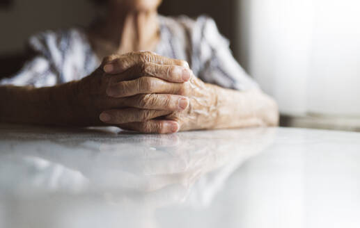 Senior woman with clasped hands relaxing at home - JCCMF03767