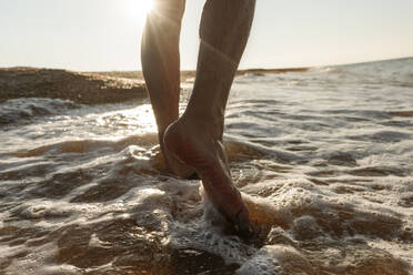 Mann geht im Wasser am Strand - EYAF01726