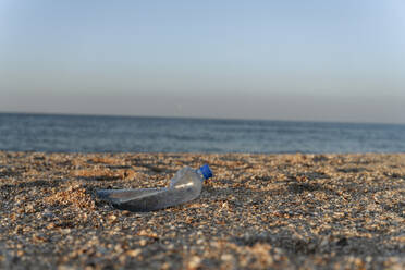 Plastic bottle on sand at beach during sunny day - EYAF01727