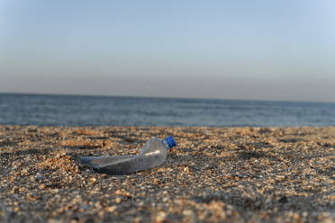 Plastikflasche auf Sand am Strand an einem sonnigen Tag - EYAF01727