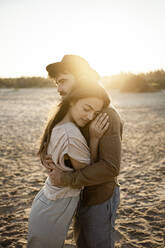 Paar umarmt am Strand stehend - RCPF01226