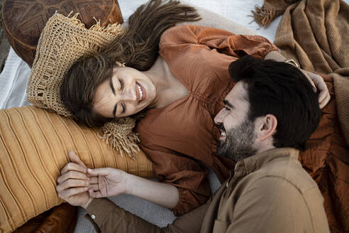 Smiling couple looking at each other while resting on picnic blanket - RCPF01238