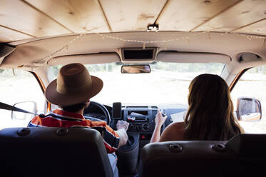 Rückansicht eines anonymen Paares von Reisenden, die mit einem Van unterwegs sind und einen Roadtrip im Sommer genießen - ADSF29513